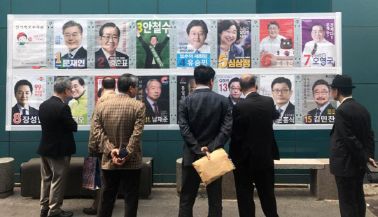 제19대 대통령 선거를 15일 앞둔 24일 오후 서울 중구에서 유권자들이 선거 벽보를 보고 있다. 헌정 사상 첫 직선제 보궐선거인 만큼 대선 후보들의 정책 방향에 대한 관심이 어느 때보다 높다.  연합뉴스